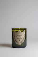 Candela artigianale in bottiglia Dom Pérignon Vintage riciclata con vetro verde e cera bianca su sfondo chiaro