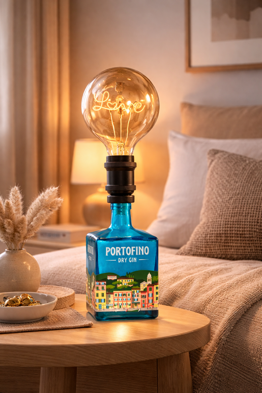 Lampada artigianale da tavolo in bottiglia di gin Portofino riciclata con lampadina vintage a luce calda, ambientata in salotto moderno di design con arredi minimal e toni neutri.
