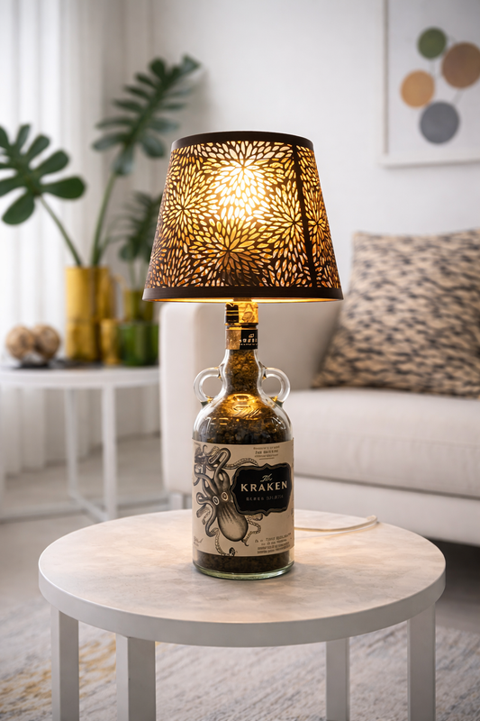 Lampada da tavolo artigianale con bottiglia Kraken rum e paralume decorativo, accesa su tavolino in marmo in salotto moderno luminoso