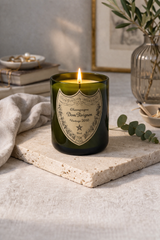 Candela Dom Pérignon riciclata accesa su tavolino in marmo in soggiorno elegante con atmosfera calda e rilassante