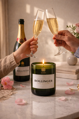 Candela Bollinger riciclata accesa con bottiglia di champagne e due persone che brindano con calici in ambiente caldo