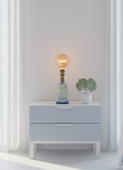 Lampada artigianale Gin Mare con lampadina “Dream” accesa, su tavolino in marmo in salotto moderno luminoso con arredi neutri e stile elegante