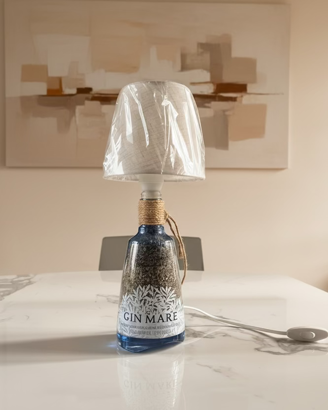 Lampada da tavolo realizzata con bottiglia di gin riciclata, con paralume in tessuto beige e corda decorativa