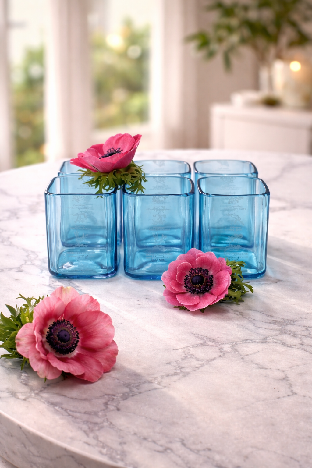 Set bicchieri in vetro blu da bottiglie Bombay Gin riciclate su tavolo apparecchiato elegante