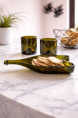 Set aperitivo in vetro verde da bottiglie riciclate con piatto e bicchieri design su tavolo in marmo