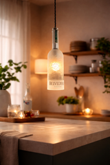 Lampada a sospensione artigianale in bottiglia Belvedere Vodka accesa sopra isola cucina in marmo, ambiente moderno luminoso con design minimal