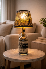Lampada artigianale in bottiglia Kraken con luce calda e paralume traforato, inserita in ambiente living moderno ed eclettico dai toni chiari