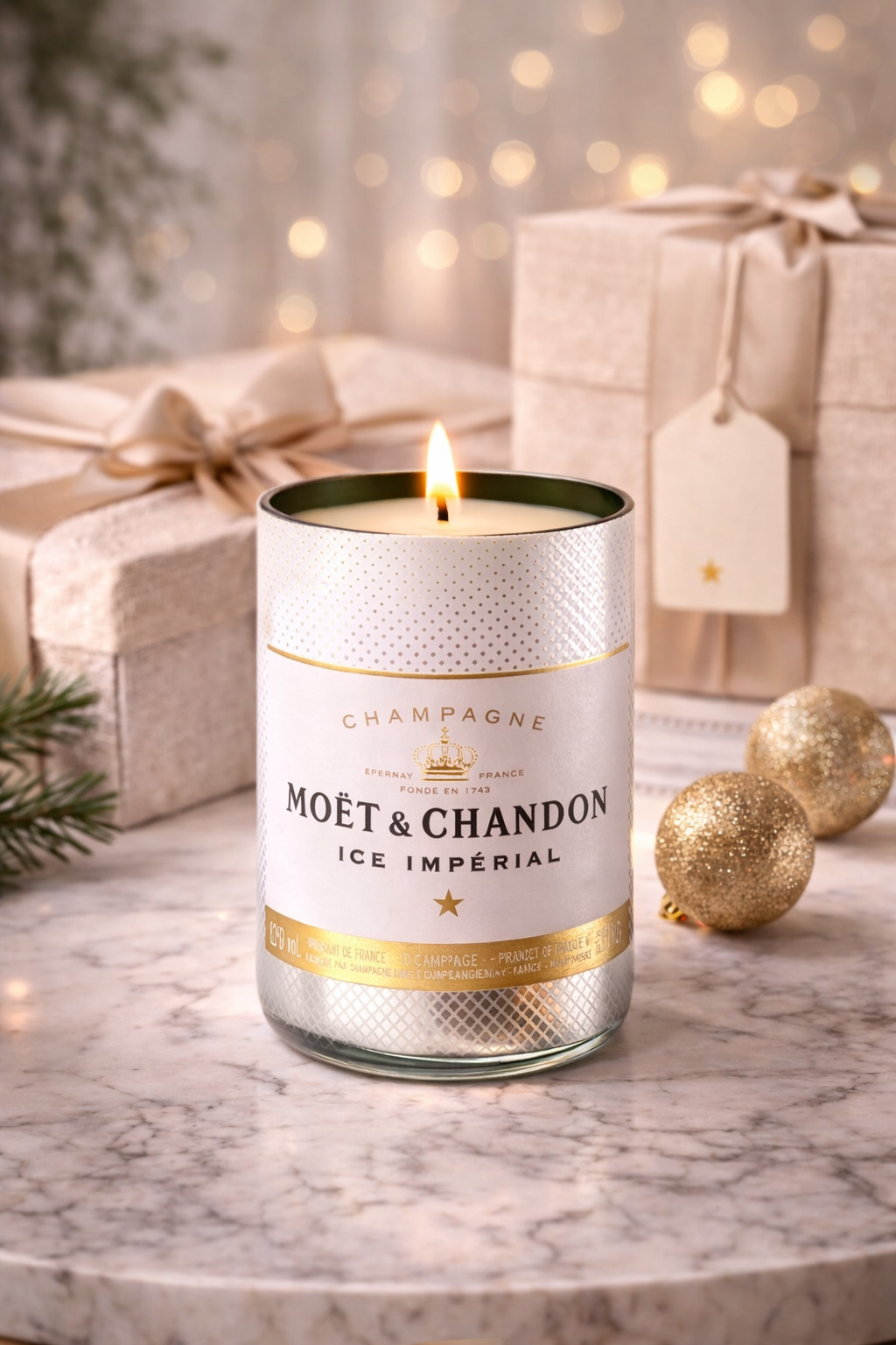 Candela Moët & Chandon in vetro riciclato accesa con confezioni regalo eleganti e dettagli oro in ambiente luminoso