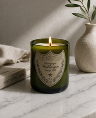 Candela Dom Pérignon in vetro riciclato accesa su piano in pietra con elementi decorativi neutri e luce naturale