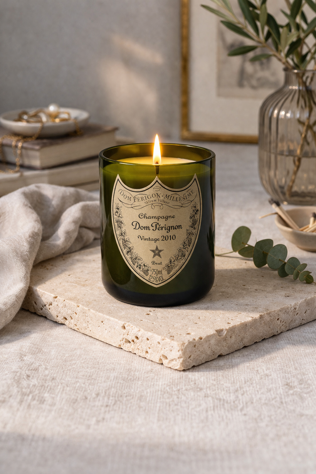 Candela Dom Pérignon riciclata accesa su tavolino in marmo in soggiorno elegante con atmosfera calda e rilassante