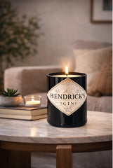 Candela Hendrick’s Gin riciclata accesa su tavolino in marmo in soggiorno accogliente con libri e luce soffusa
