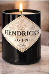 Candela artigianale in bottiglia Hendrick’s Gin riciclata con cera bianca e luce calda su sfondo chiaro